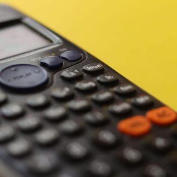 Close-up of a black calculator against a yellow background