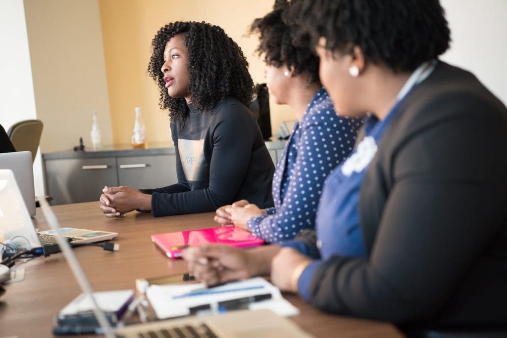 Three women sitting at a desk for a meeting