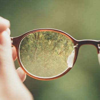 A close up view through a pair of glasses looking at trees