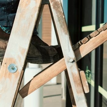 A close up of a handyman climbing a wooden ladder