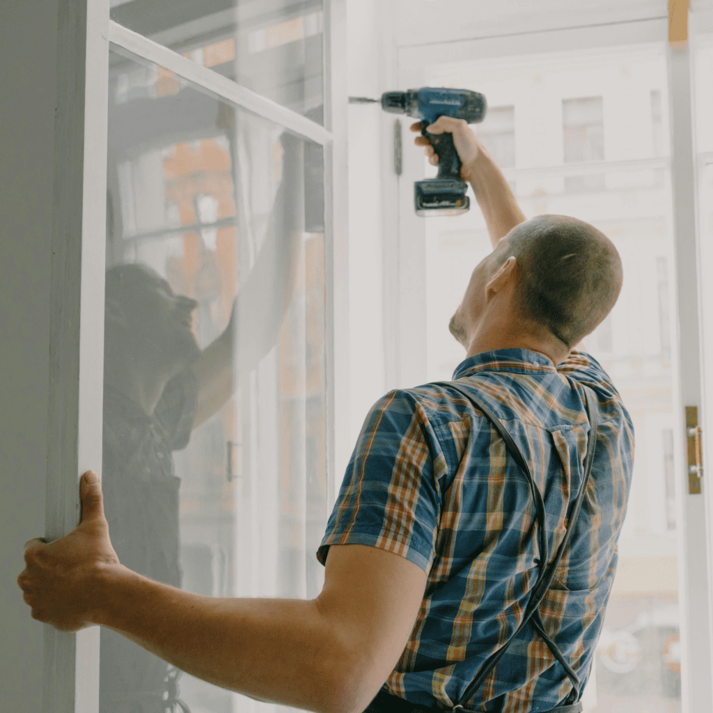 A man using a drill to fix a doorway